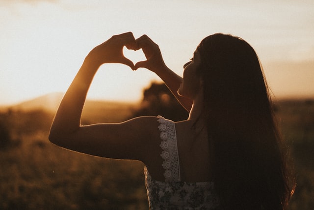 Self-Care for Migraine; an aesthetic shot of a person making a heart symbol with their hands