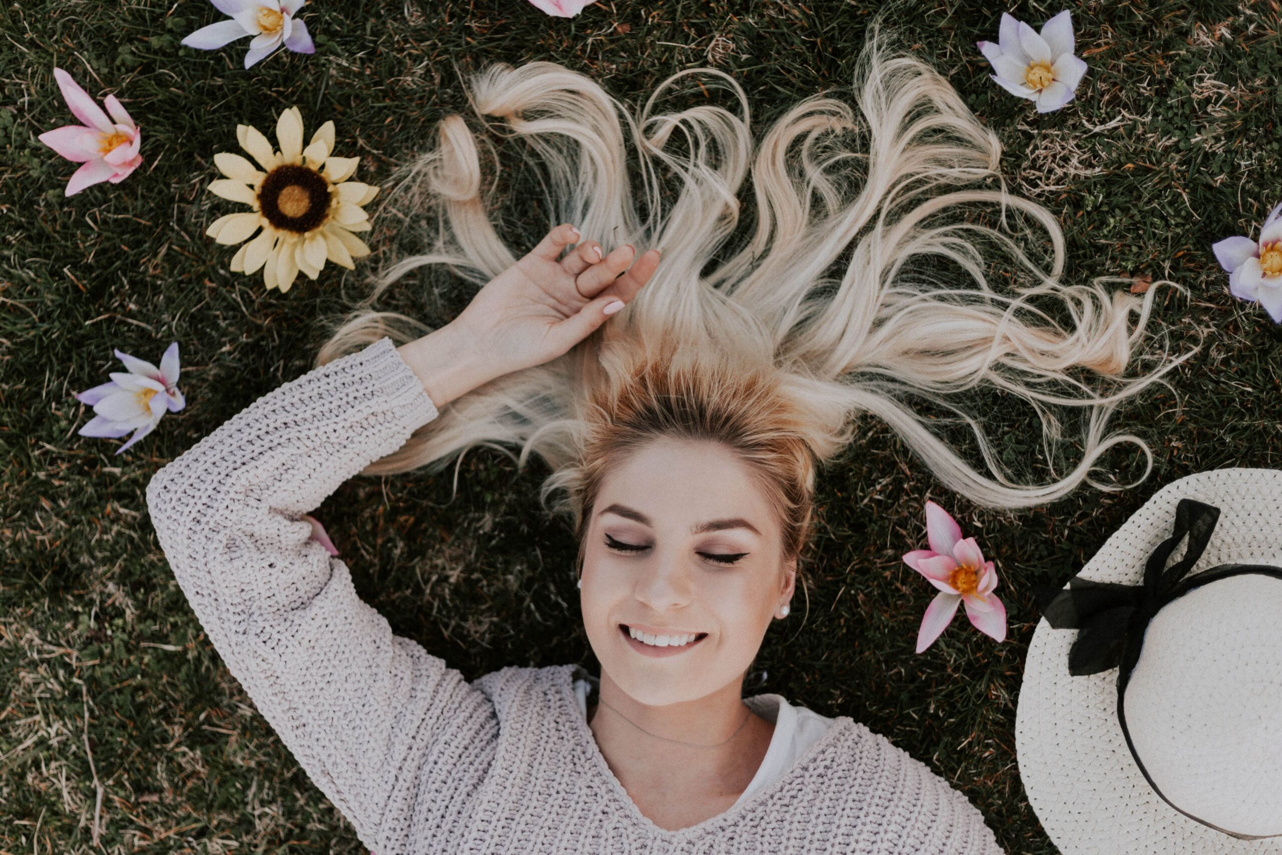 migraine hypnotherapy, woman laying on  grass surrounded with flowers