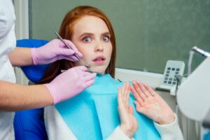 Hynptherpay for dental anxiety: A woman looks shocked getting her tooth fixed by a dentist