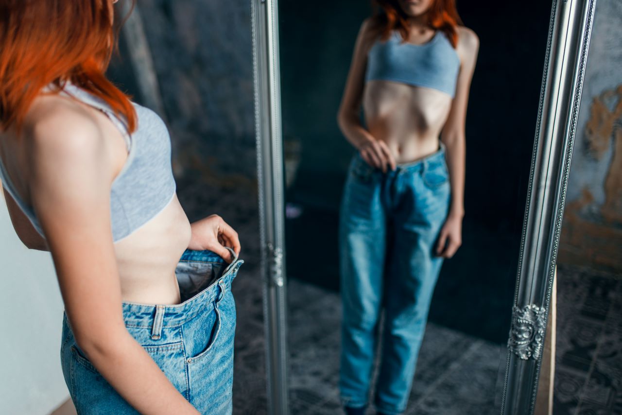 anorexia treatment, Thin woman tries on big size jeans