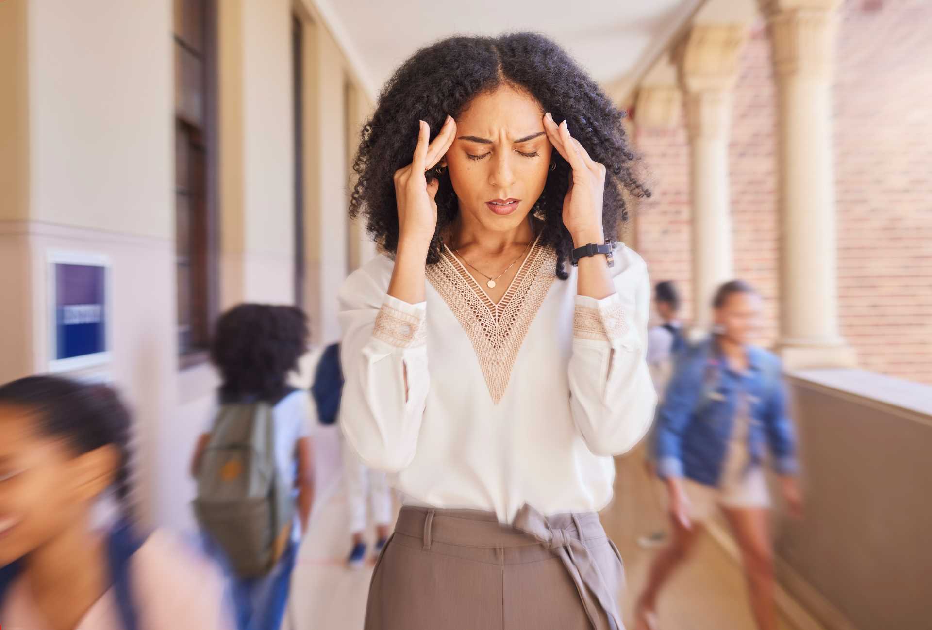 A woman holding her head with both hands with kids in the background.