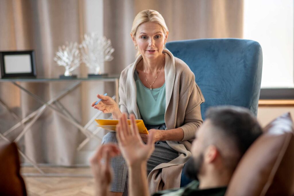 A therapist sitting in her clinic while talking to a male patient.