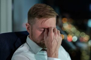 A Caucasian man looking distraught and holding his hand to his face.